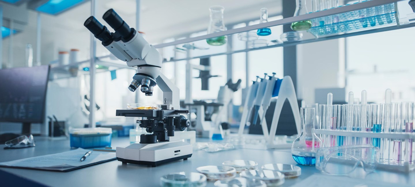 Photo of laboratory equipment, including a microscope, plates, flasks and tubes.