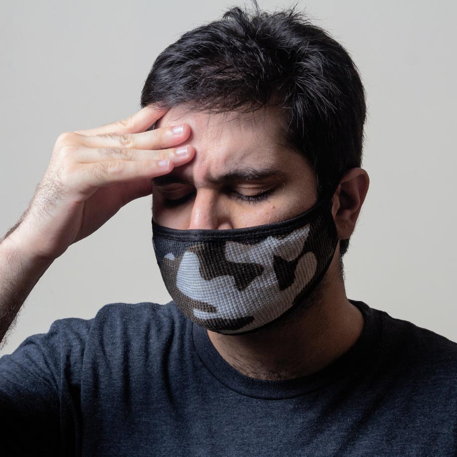 Picture of a man wearing a mask, touching his head.