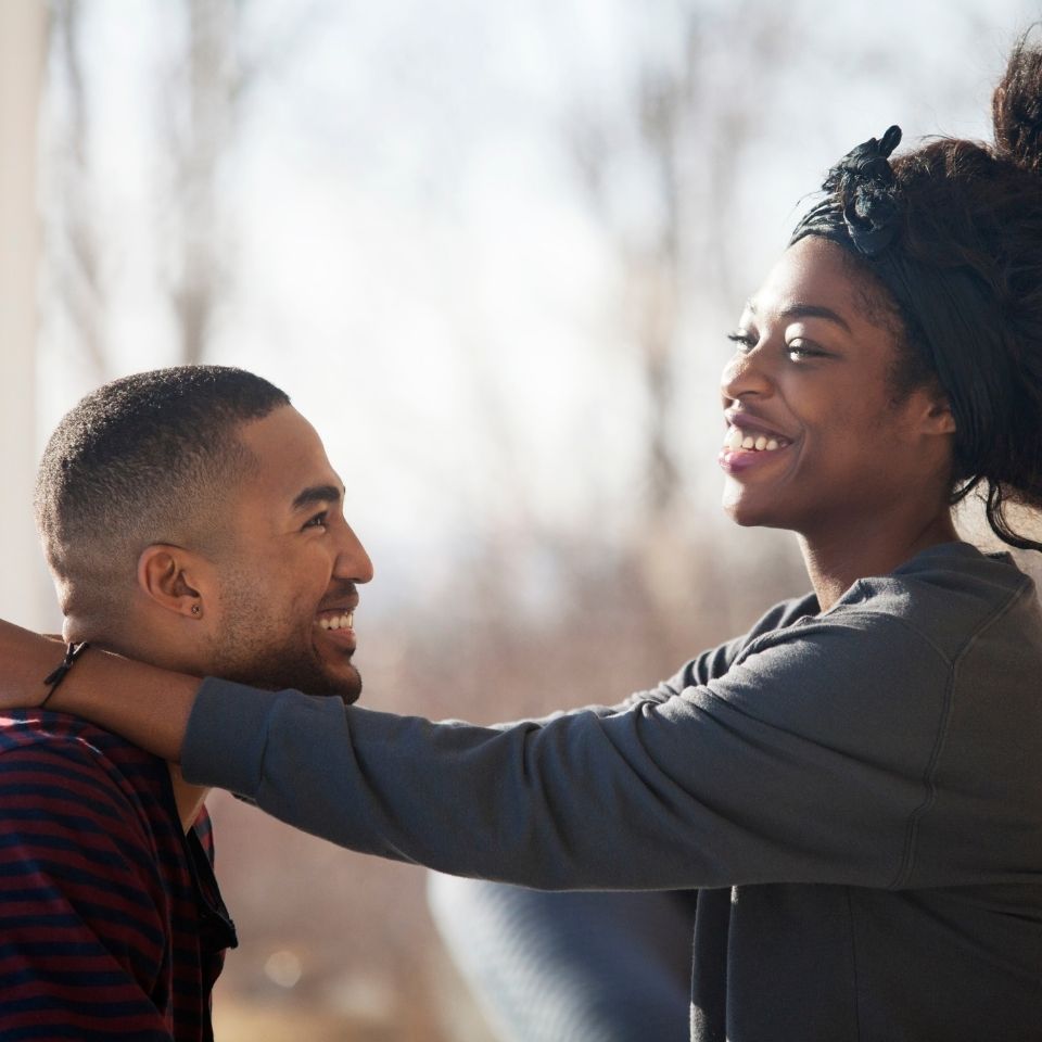 Young man and woman smiling and hugging